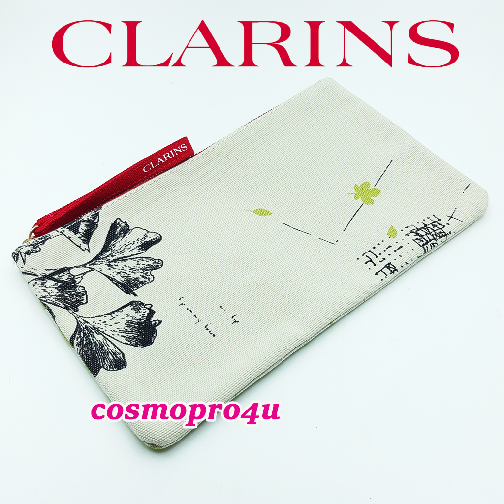 กระเป๋า CLARINS คลาแรงส์ สีน้ำตาลอ่อน-เขียว ด้านนึงเป็นผ้าพื้นใบไม้สีดำ อีกด้านลายใบไม้สีเขียว มีโลโก้ CLARINS ที่สายคล้องมือ ทรงแบน 9x5 นิ้ว